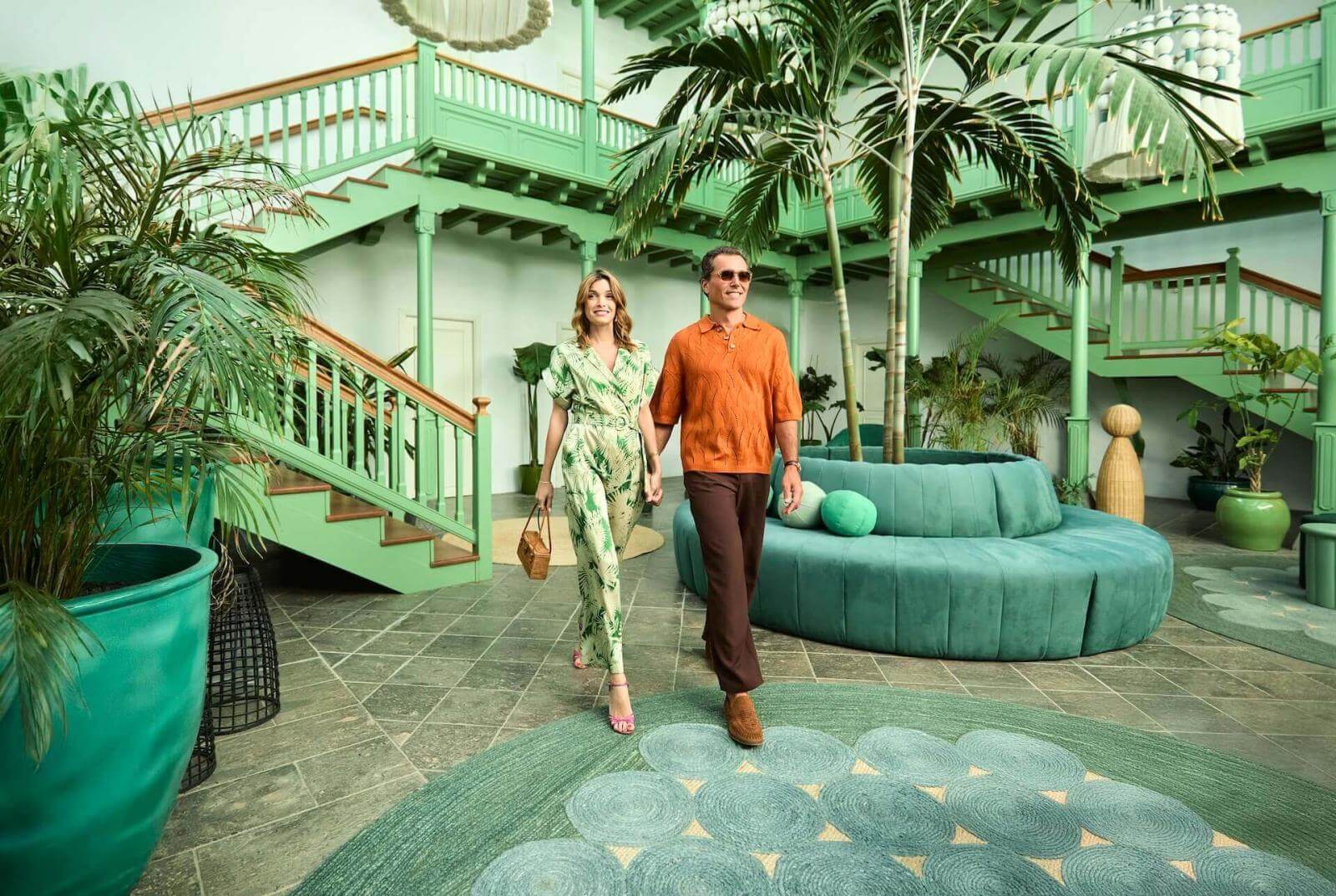 Ein Paar geht durch einen hellen, von der traditionellen kanarischen Architektur inspirierten Innenhof mit tropischer Vegetation.