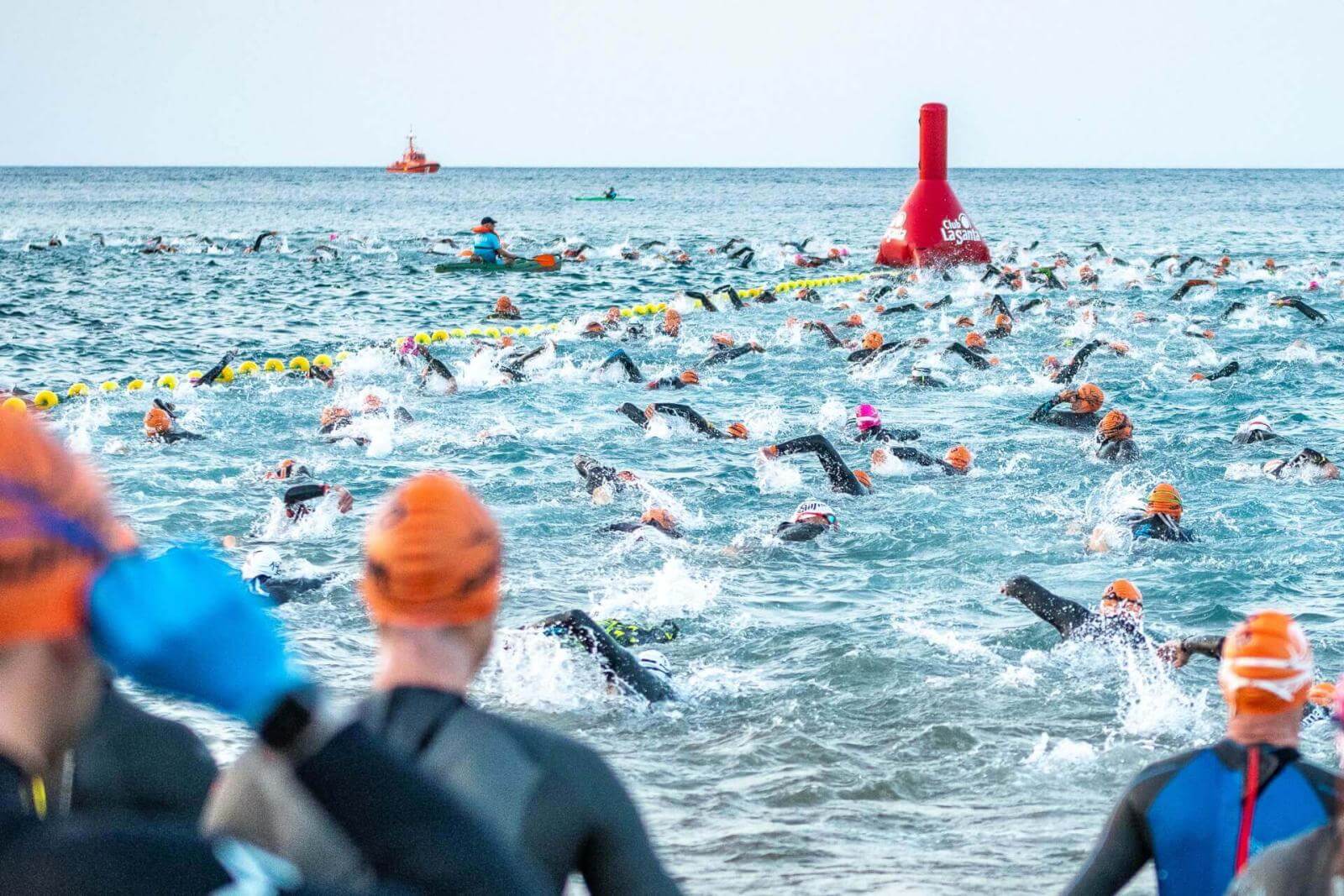 Mehrere Schwimmer nehmen im offenen Wasser an einem Wettkampf teil, die Strecke wird durch Bojen markiert.