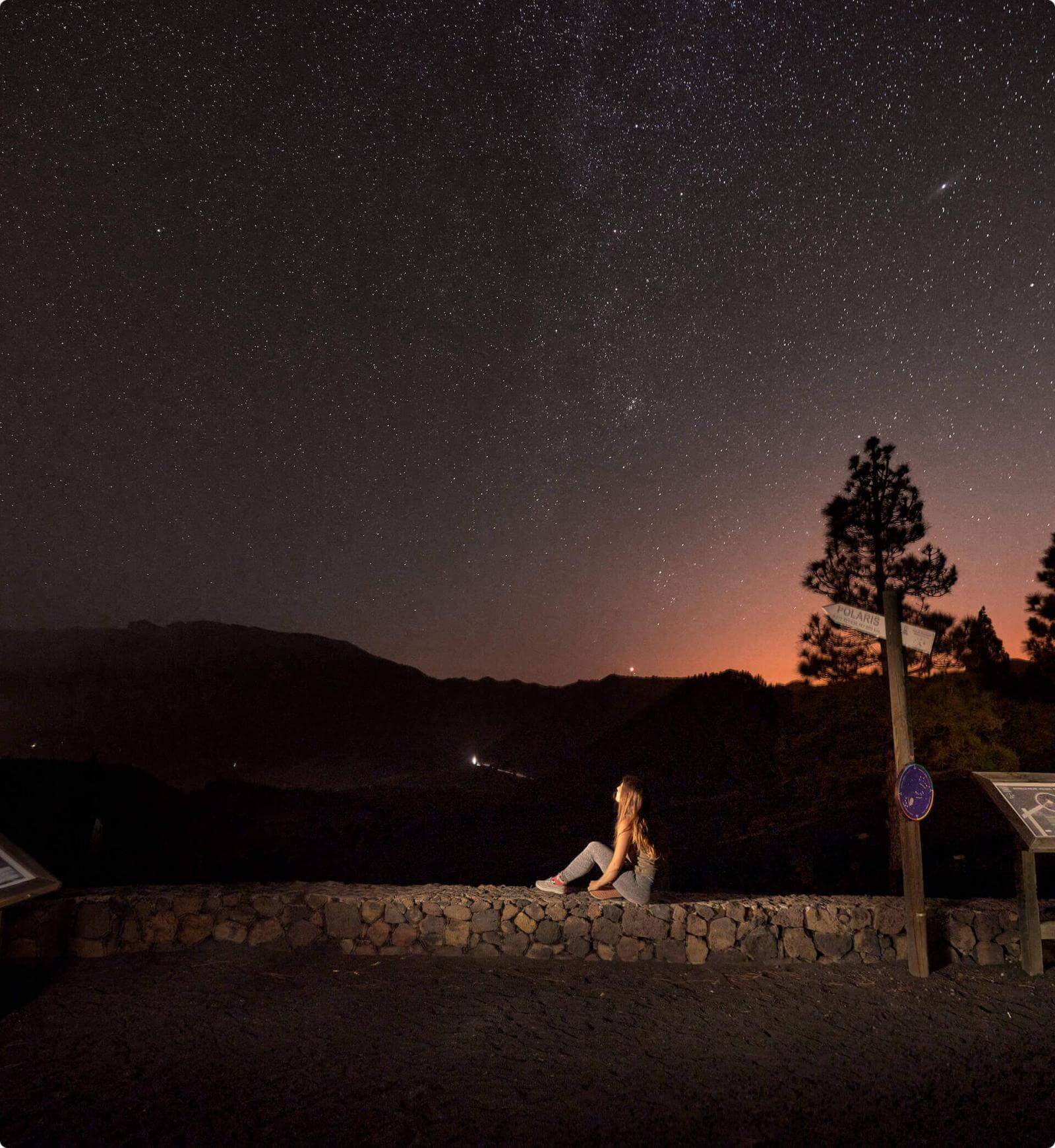 Sternenhimmel am Aussichtspunkt Llano del Jable, La Palma, mit Bergsilhouetten und einem staunenden Menschen.