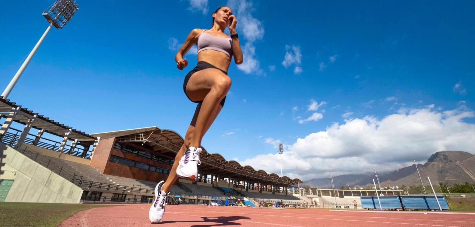 Ein Sportler trainiert auf einer Leichtathletikbahn.
