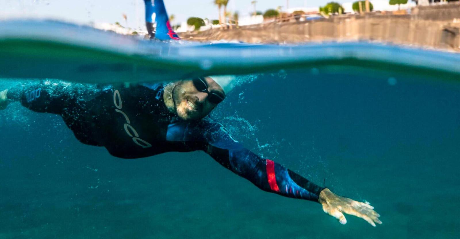 Person schwimmt im Freiwasser mit Neoprenanzug.