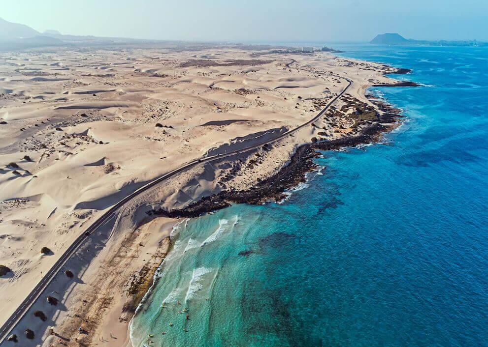 Luftaufnahme der Dünen von Corralejo auf Fuerteventura mit weitläufigen Sandflächen am türkisfarbenen Meer.